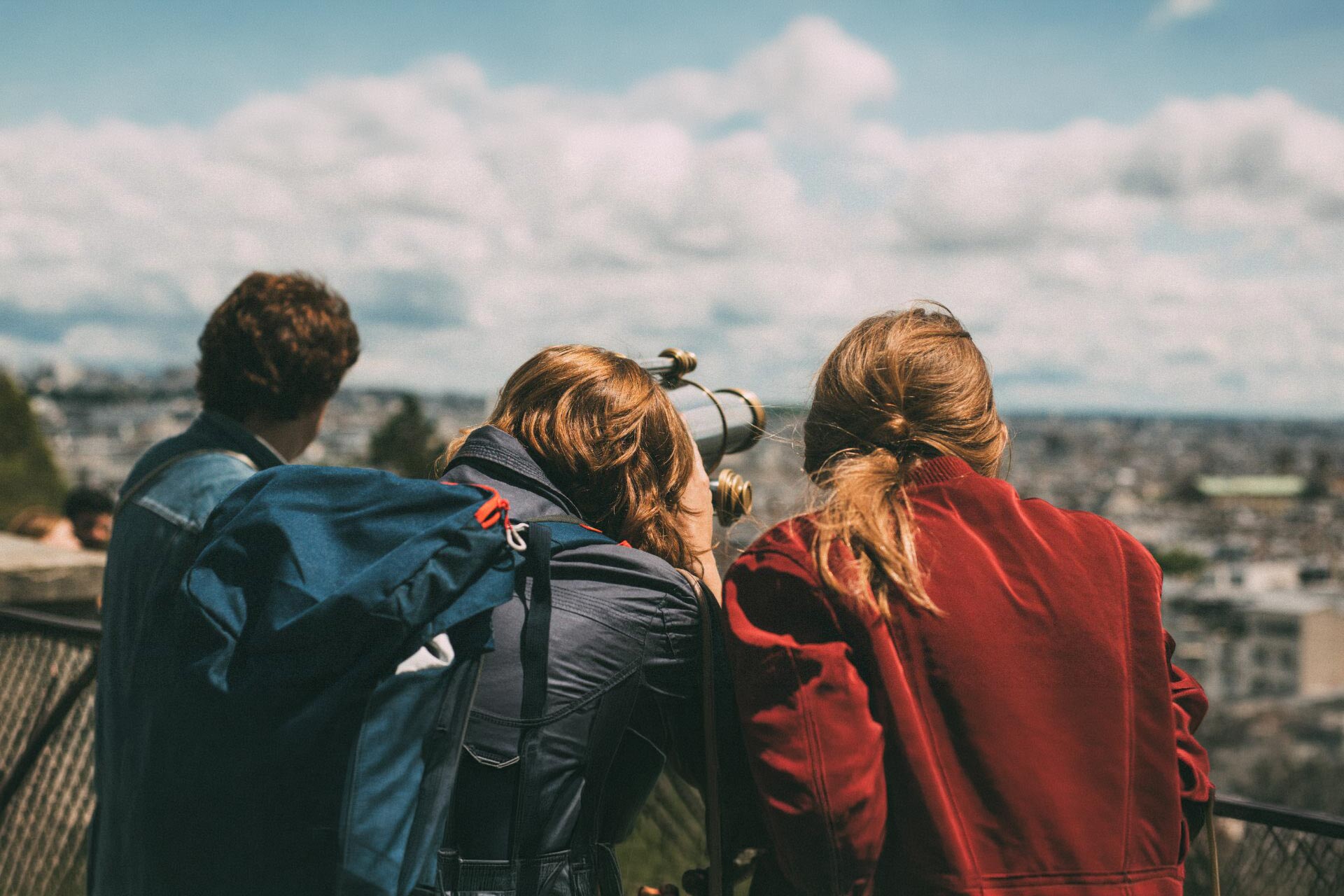 groupe de jeunes qui regarde un paysage urbain au travers d'une longue vue